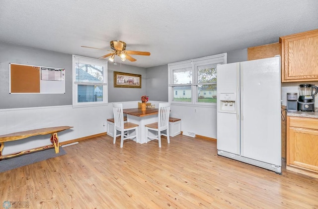 dining space with light hardwood / wood-style flooring, a textured ceiling, and ceiling fan