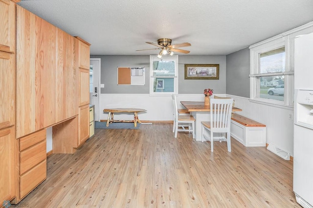 dining room with a textured ceiling, light wood-type flooring, and ceiling fan