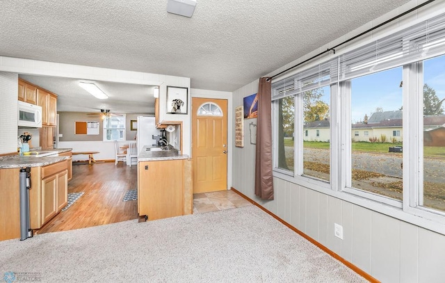 kitchen featuring light hardwood / wood-style flooring, a textured ceiling, and ceiling fan