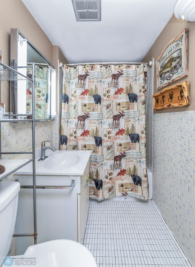 full bathroom featuring toilet, shower / bath combo with shower curtain, vanity, and tile walls