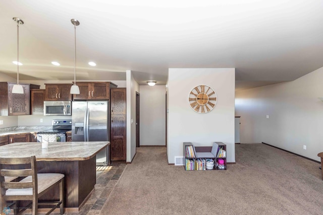 kitchen featuring a kitchen island, appliances with stainless steel finishes, a kitchen breakfast bar, dark carpet, and decorative light fixtures