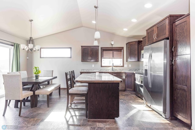 kitchen featuring a kitchen breakfast bar, stainless steel appliances, vaulted ceiling, a center island, and decorative light fixtures