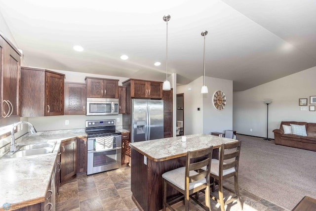 kitchen with sink, a center island, stainless steel appliances, pendant lighting, and dark carpet