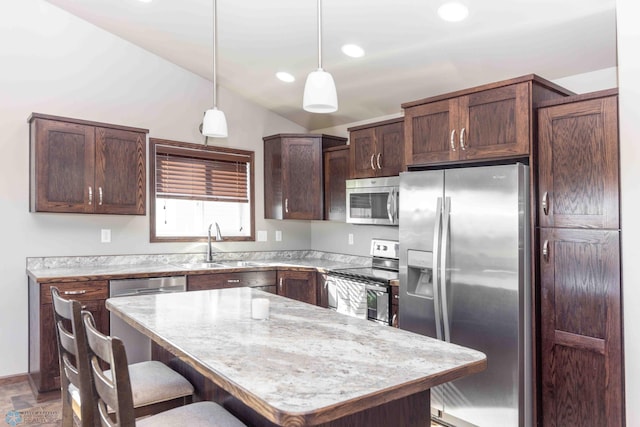 kitchen featuring a kitchen island, sink, a breakfast bar, pendant lighting, and appliances with stainless steel finishes