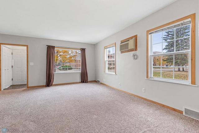 carpeted empty room featuring a wall unit AC and a healthy amount of sunlight