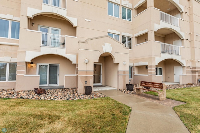 exterior space featuring a front lawn and a balcony