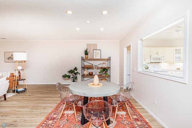 dining area featuring light hardwood / wood-style floors, ornamental molding, and ceiling fan