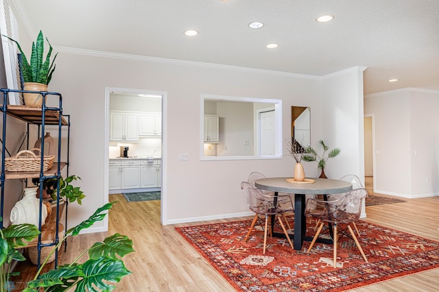 dining room with ornamental molding and light hardwood / wood-style floors