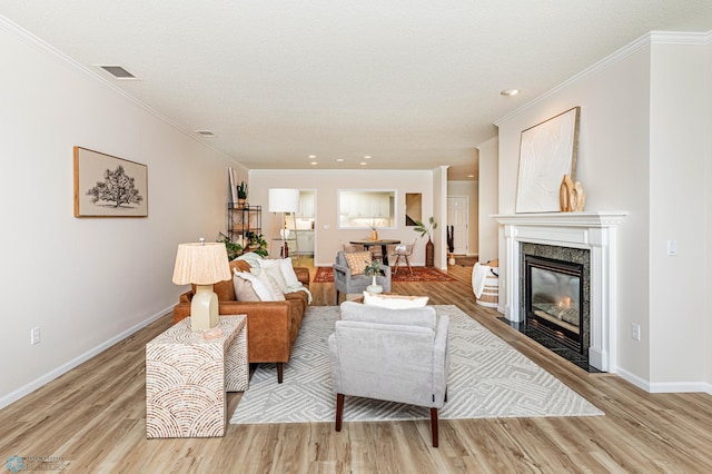 living room with light hardwood / wood-style floors, crown molding, and a textured ceiling