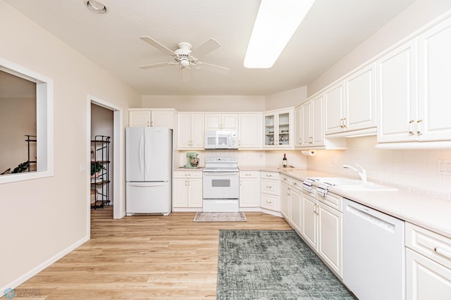 kitchen with sink, white cabinets, light wood-type flooring, and white appliances