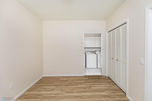 hall with light hardwood / wood-style floors, a textured ceiling, and washer and clothes dryer