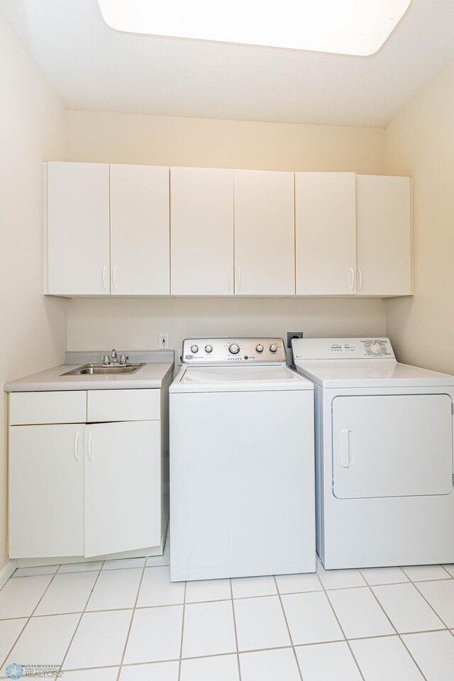 laundry area featuring sink, independent washer and dryer, light tile patterned flooring, and cabinets