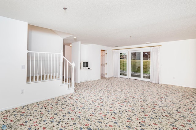 unfurnished living room featuring carpet flooring and a textured ceiling