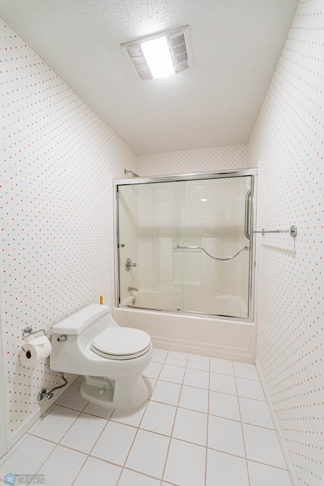 bathroom featuring toilet, a textured ceiling, enclosed tub / shower combo, and tile patterned flooring