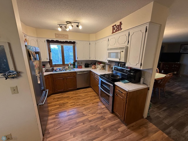 kitchen featuring hardwood / wood-style floors, stainless steel appliances, sink, and a textured ceiling