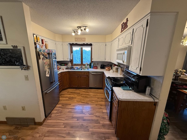 kitchen with white cabinets, dark hardwood / wood-style flooring, appliances with stainless steel finishes, a textured ceiling, and sink