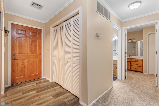 hallway with crown molding, sink, and light wood-type flooring