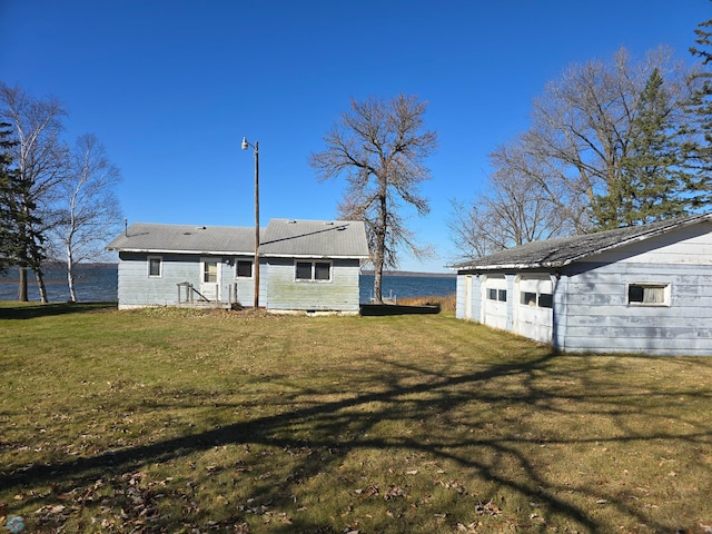 back of property with a water view and a lawn