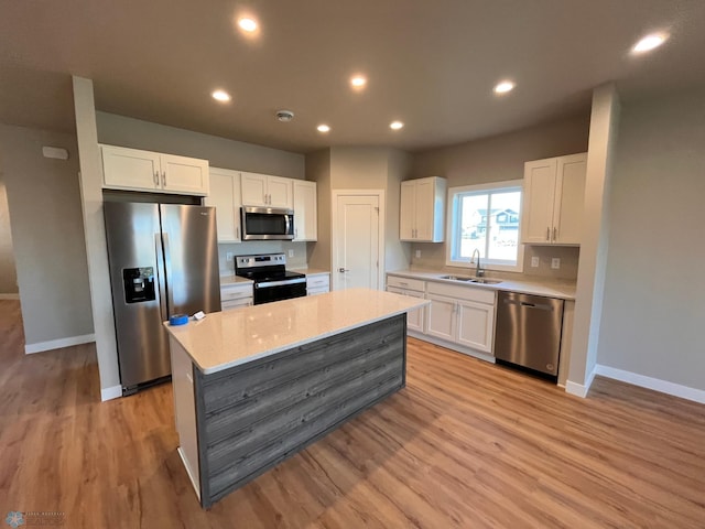 kitchen featuring appliances with stainless steel finishes, light hardwood / wood-style flooring, white cabinetry, and sink