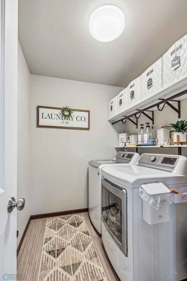 laundry area with light hardwood / wood-style flooring and washing machine and dryer