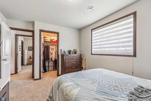 bedroom with a closet, light carpet, and a spacious closet