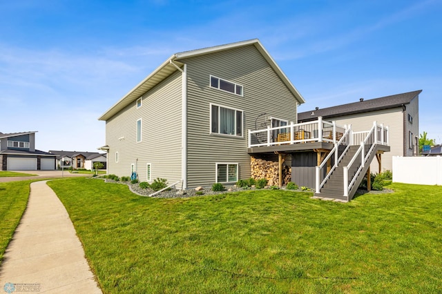 rear view of property featuring a wooden deck, a garage, and a lawn