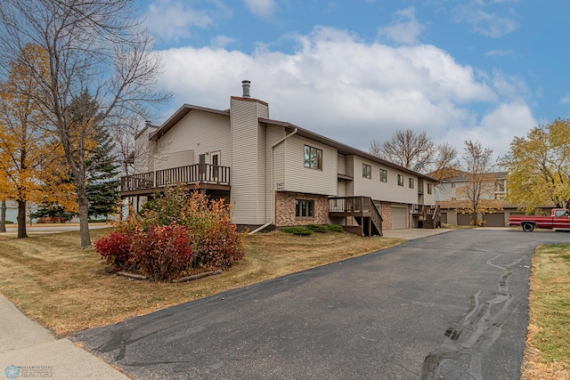 view of side of home with a wooden deck, a garage, and a lawn