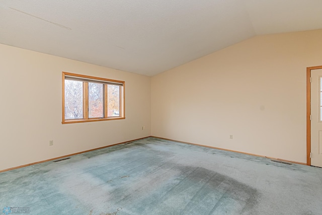 carpeted empty room featuring a textured ceiling and vaulted ceiling