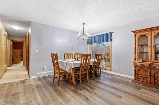 dining area with hardwood / wood-style floors, a textured ceiling, and a chandelier