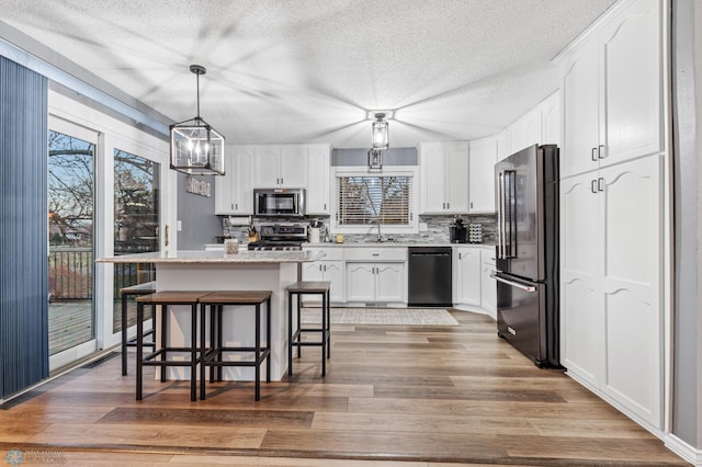 kitchen with hardwood / wood-style floors, a center island, stainless steel appliances, and white cabinetry