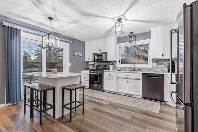 kitchen featuring a healthy amount of sunlight, a center island, stainless steel appliances, and white cabinetry