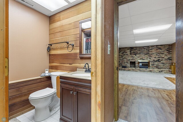 bathroom with vanity, wooden walls, and toilet