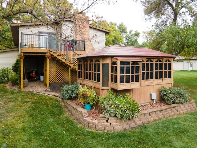 rear view of property featuring a yard, a sunroom, and a deck