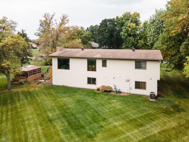 back of house featuring a wooden deck, a lawn, and central AC unit