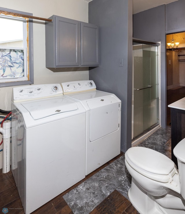 clothes washing area featuring a notable chandelier, washer and clothes dryer, and dark hardwood / wood-style flooring