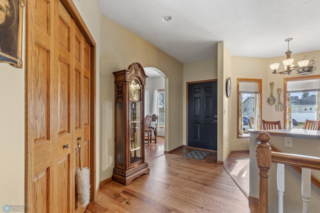 foyer entrance featuring a chandelier, a textured ceiling, and light wood-type flooring