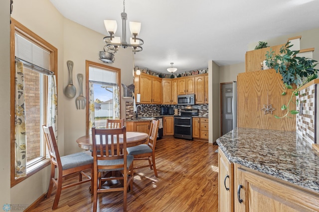 kitchen featuring tasteful backsplash, hanging light fixtures, appliances with stainless steel finishes, an inviting chandelier, and dark wood-type flooring