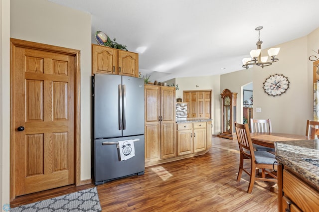 kitchen with stainless steel fridge, light hardwood / wood-style flooring, pendant lighting, and an inviting chandelier