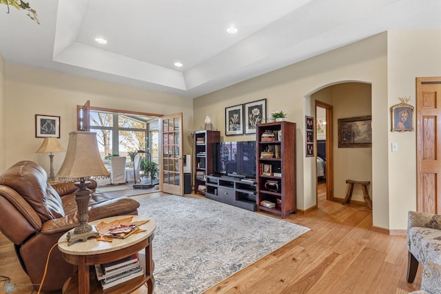 living room with light hardwood / wood-style flooring and a raised ceiling