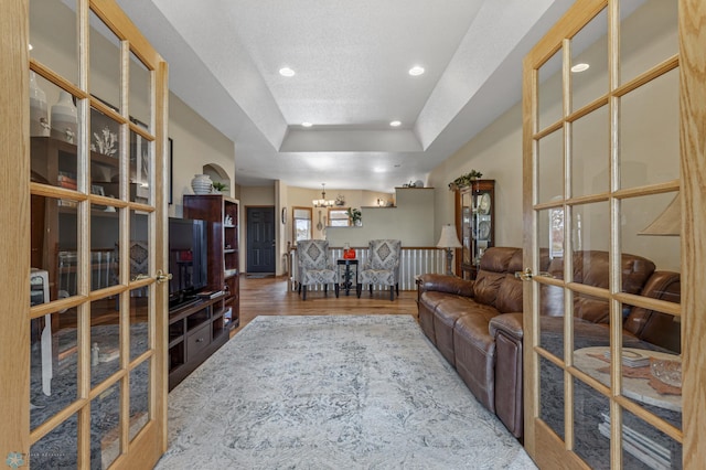 living room featuring hardwood / wood-style flooring, a chandelier, and a tray ceiling