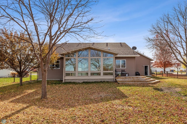 rear view of house featuring a yard and a sunroom