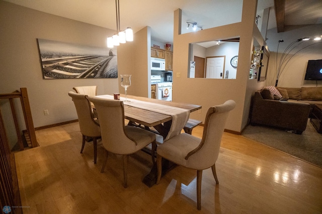 dining room featuring light hardwood / wood-style flooring, a notable chandelier, and vaulted ceiling