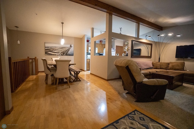 living room featuring light wood-type flooring and vaulted ceiling with beams