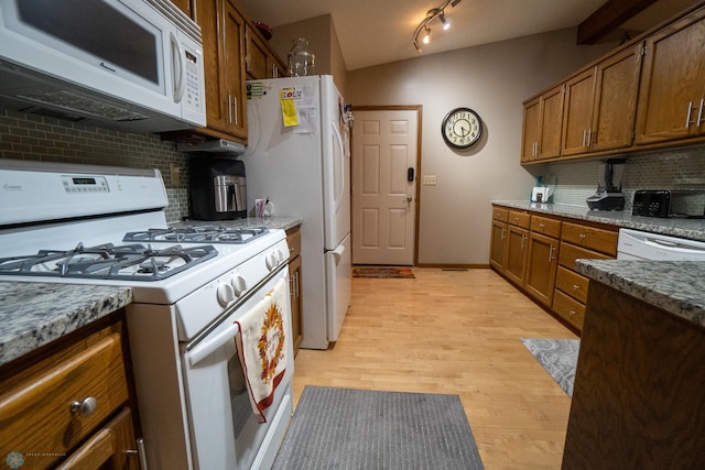 kitchen featuring white appliances, vaulted ceiling, decorative backsplash, and light hardwood / wood-style flooring