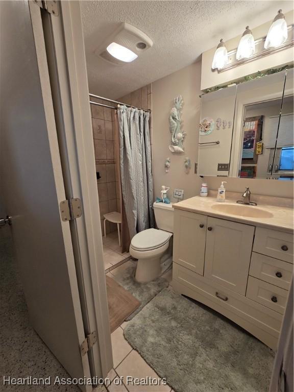 bathroom featuring toilet, a shower with curtain, a textured ceiling, vanity, and tile patterned flooring