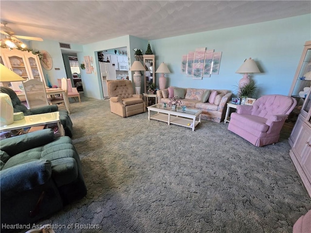 living room with ceiling fan, carpet flooring, and a textured ceiling