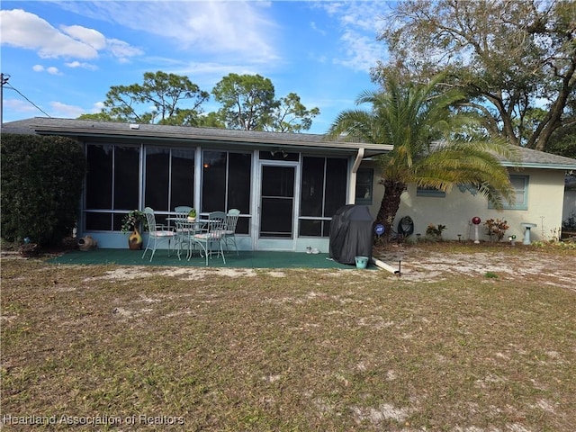 back of house featuring a sunroom and a lawn