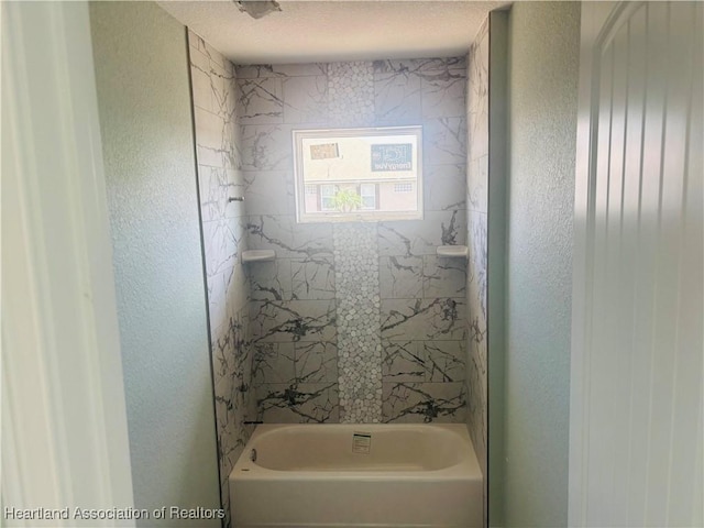 bathroom featuring shower / bathing tub combination and a textured wall