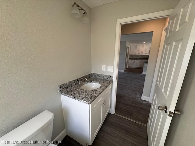 bathroom featuring vanity, hardwood / wood-style flooring, and toilet