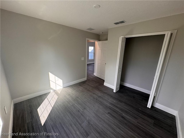 unfurnished bedroom with dark wood-type flooring and a closet